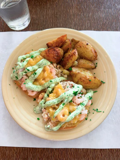 An open-faced seafood melt with shrimp, crab, and herbed aioli, served with roasted potatoes