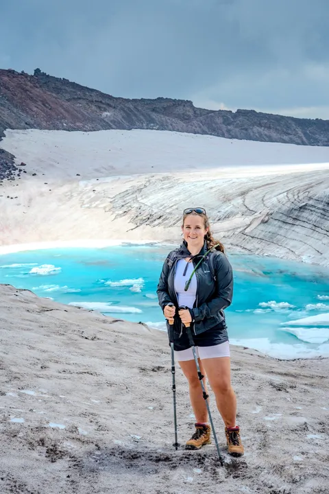 Marin on a Cascades summit above a turquoise glacial lake